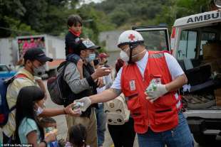 volontario della croce rossa dona del cibo ai migranti in honduras