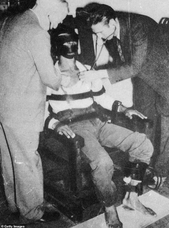 1940: Un medico controlla il battito cardiaco di un criminale mentre è seduto sulla sedia elettrica