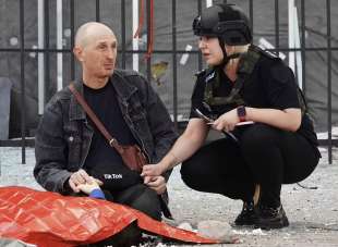 poliziotta consola un padre disperato accanto al corpo del figlio ucciso dai russi a kharkiv