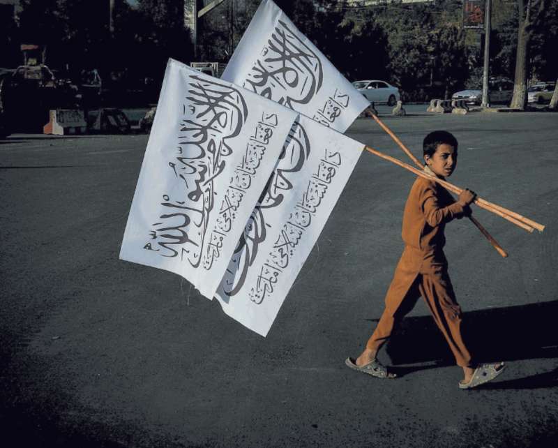 un bambino vende le bandiere dei talebani a kabul