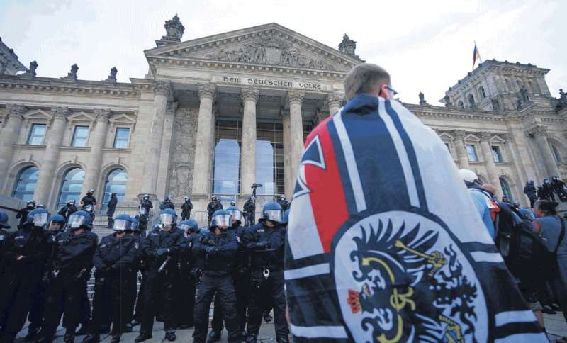 un neonazista con la bandiera imperiale tedesca di fronte al reichstag